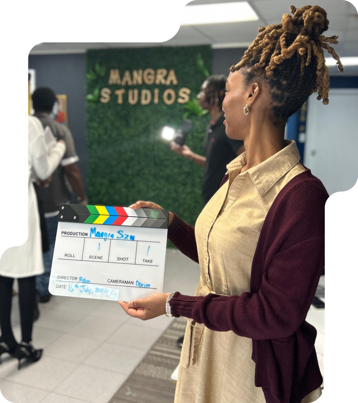A Mangra Studios producer holding a “Mangra SZN” clapperboard on set.